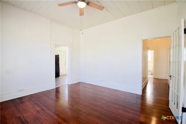 a view of a room with wooden floor and a ceiling fan