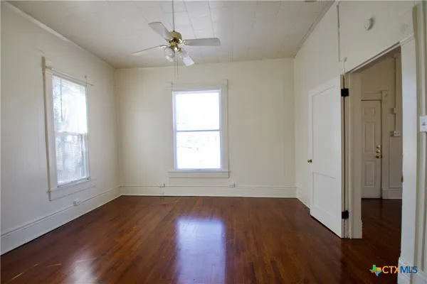a view of an empty room with wooden floor and a window