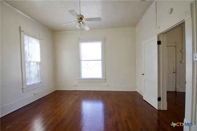 a view of an empty room with wooden floor and a window