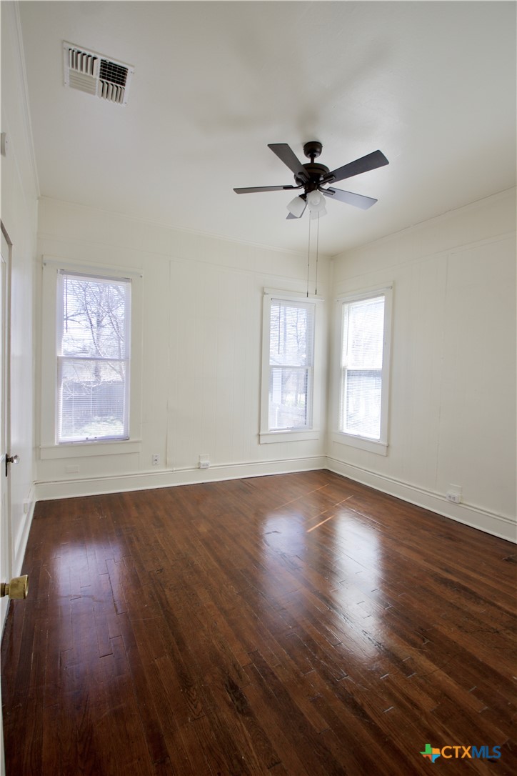 617 North 6th Street Temple, TX 76501 - Photo 30 of 38 an empty room with wooden floor a ceiling fan and windows