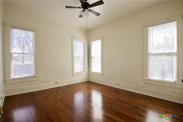 a view of an empty room with wooden floor and a window
