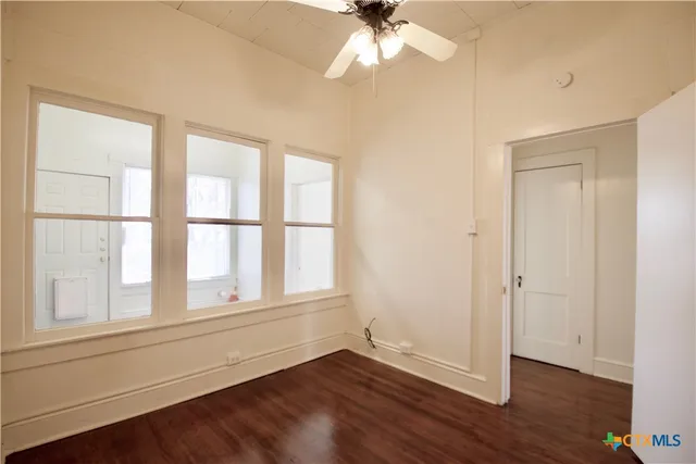 an empty room with wooden floor closet and windows