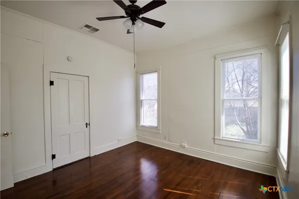 a view of an empty room with wooden floor and a window