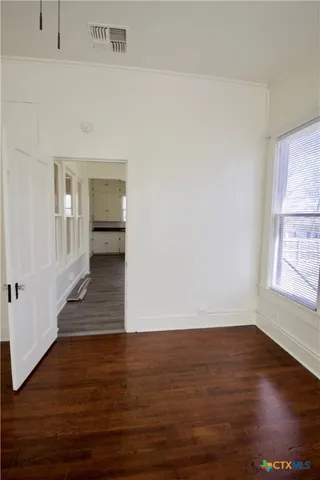 a view of an empty room with wooden floor and a window