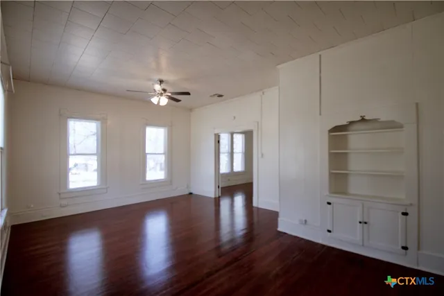 a view of an empty room with a window and wooden floor