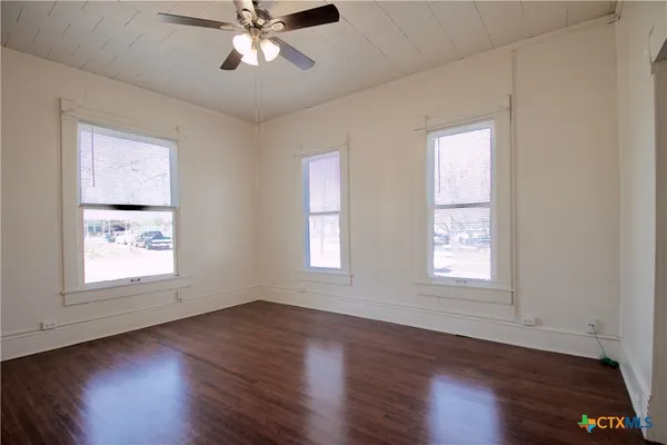 a view of an empty room with wooden floor and a window