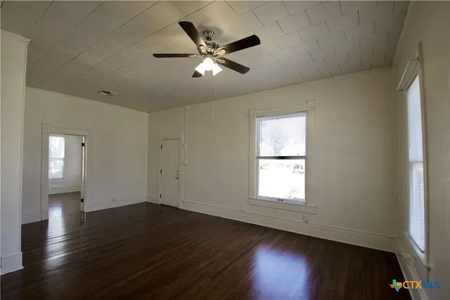 a view of wooden floor and a chandelier fan in a room