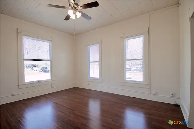 a view of an empty room with wooden floor and a window