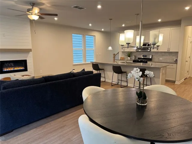 a kitchen with stainless steel appliances granite countertop a sink a stove and a dining table with wooden floor