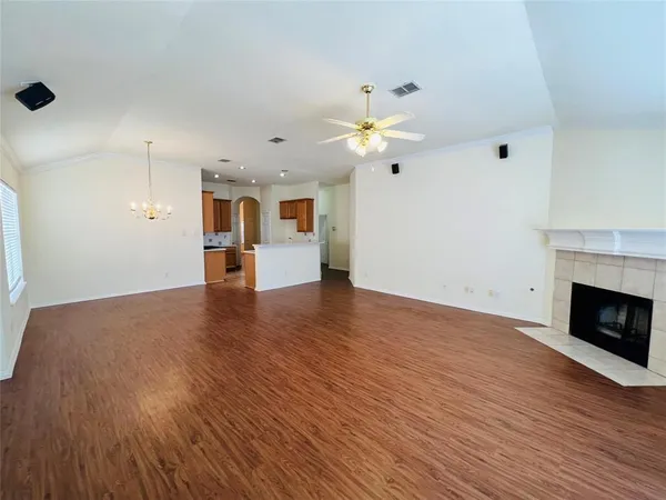 a view of an empty room with wooden floor and a fireplace