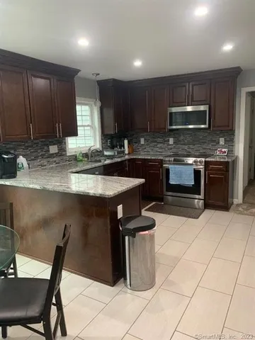 a kitchen with granite countertop a stove a sink a microwave and a dining table