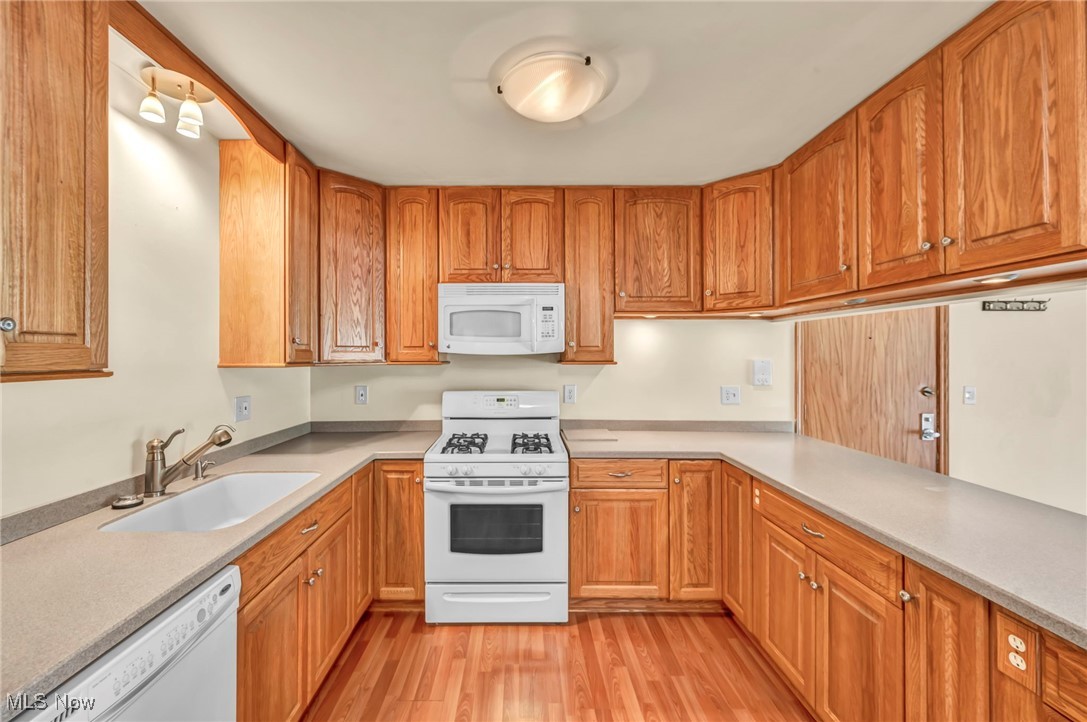 1263 Lost Nation Road, Unit 5 Willoughby, OH 44094 - Photo 14 of 26 Kitchen with white appliances, light wood-style floors, brown cabinetry, and light stone countertops