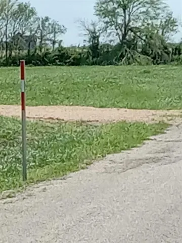 a street sign on the side of grassy field