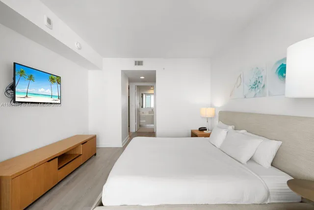 a bedroom with a bed and a lamp on dresser