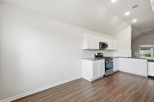 a kitchen with stainless steel appliances granite countertop a sink and a stove top oven with wooden floor