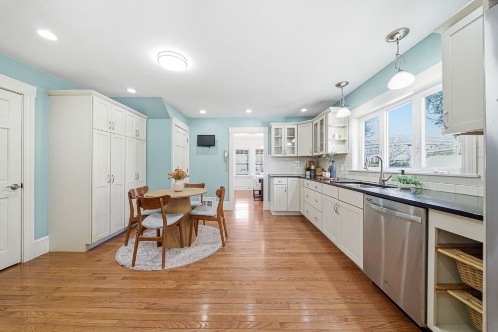 45 Marion Street Natick, MA 01760 - Photo 18 of 42 a kitchen with stainless steel appliances granite countertop a stove top oven a sink dishwasher a dining table and chairs with wooden floor