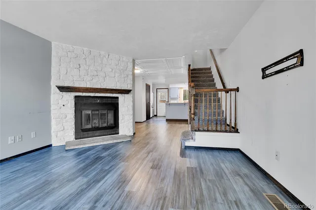a view of a livingroom with wooden floor fireplace and stairs