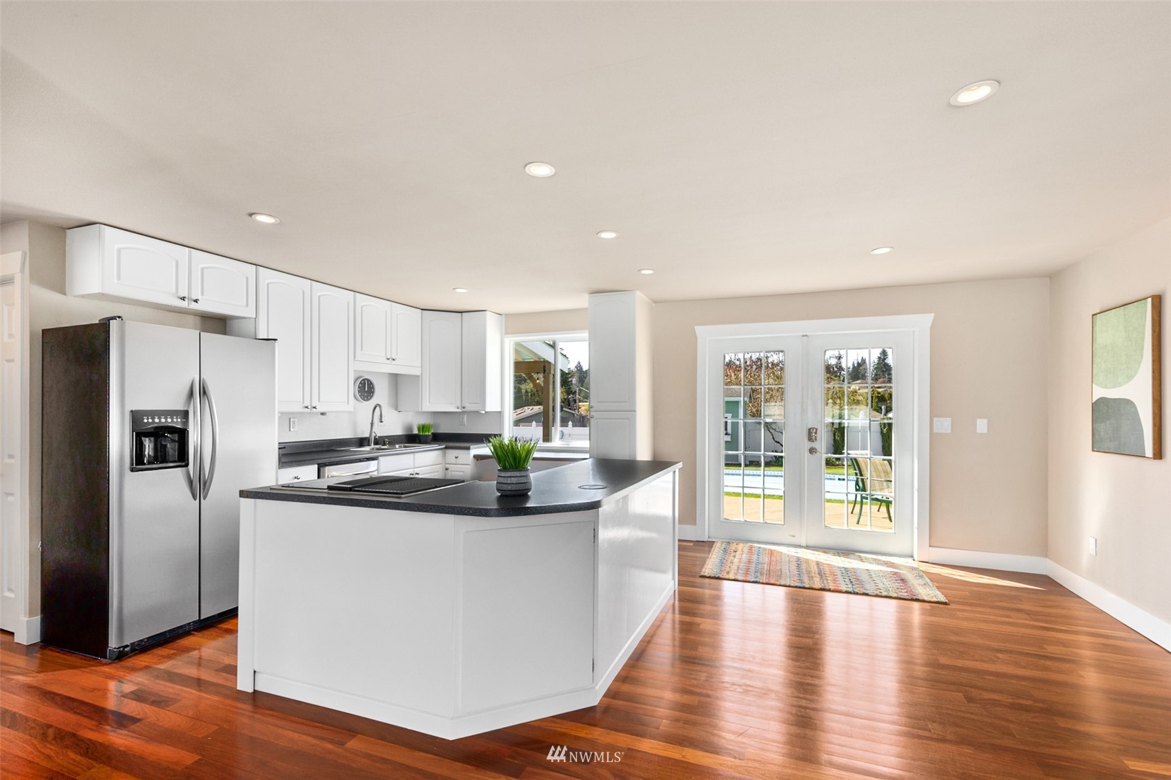 24204 Lockwood Road Bothell, WA 98021 - Photo 11 of 40 a kitchen with stainless steel appliances a refrigerator a sink dishwasher a stove and white cabinets with wooden floor next to windows