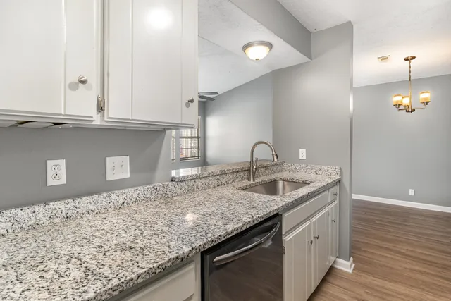 a kitchen with granite countertop a sink and a white cabinets
