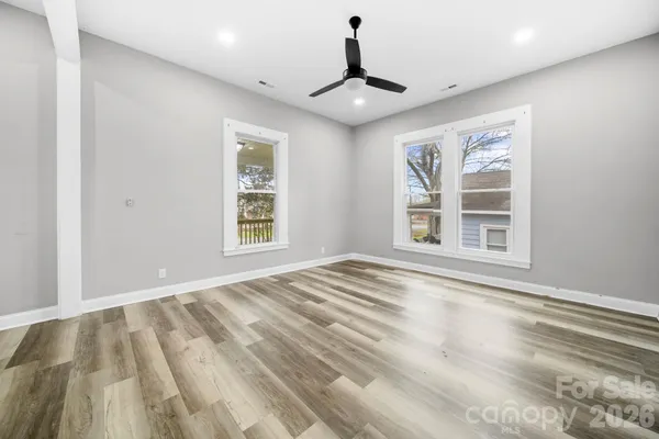 a view of an empty room with wooden floor and windows