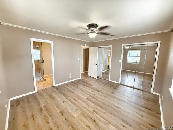 a view of empty room with wooden floor and fan
