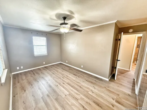 a view of empty room with wooden floor and fan