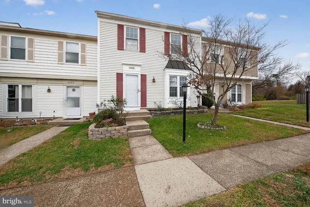 a front view of a house with a yard and potted plants