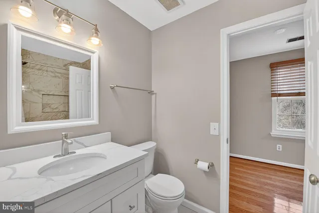 a bathroom with a granite countertop sink toilet a large mirror and a window