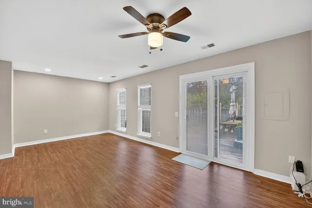 a view of an empty room with window and wooden floor