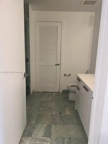a bathroom with a granite countertop toilet and a shower