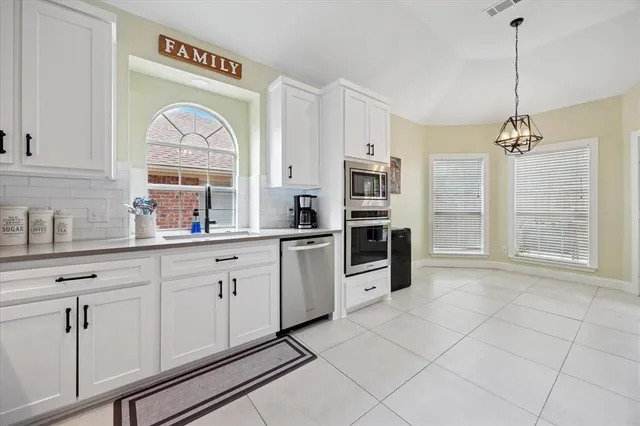 a kitchen with white cabinets and window