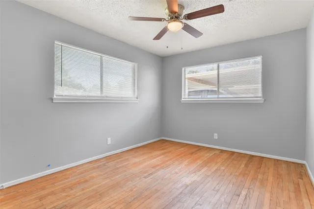 a view of room with window ceiling fan and wooden floor