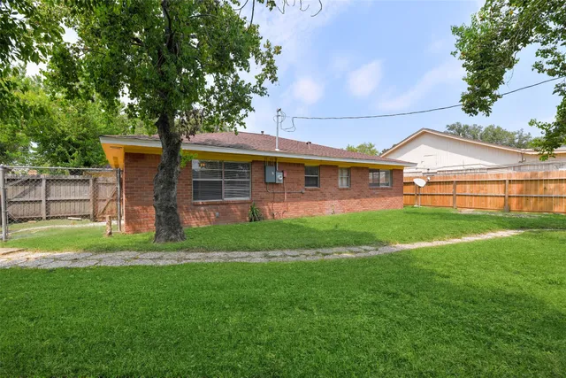 a view of a house with a big yard potted plants and large tree