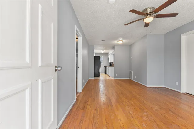 a view of hallway with a chandelier fan and a wooden floor