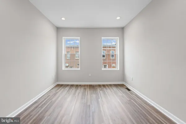 an empty room with wooden floor and windows