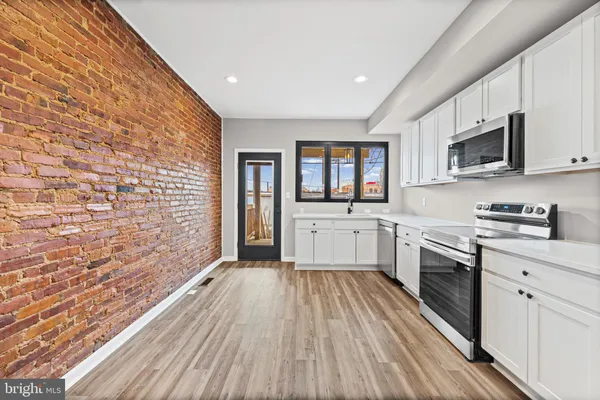 a large kitchen with cabinets wooden floor and stainless steel appliances