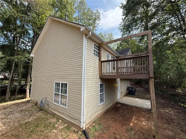 a view of small house with a deck and a floor to ceiling window