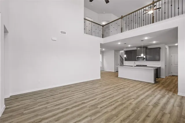 a view of large kitchen with kitchen island stainless steel appliances wooden floor and window