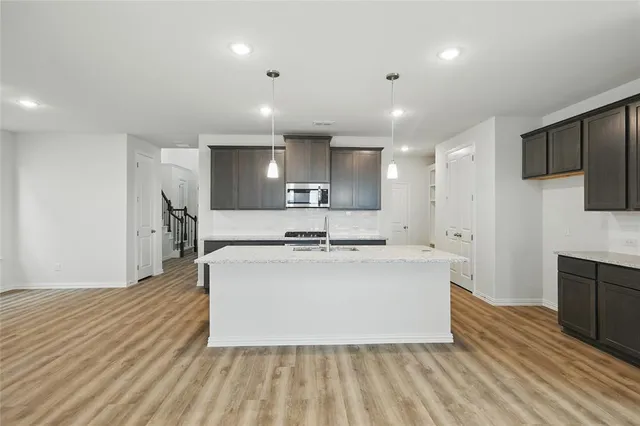 a large kitchen with stainless steel appliances a large counter top a stove and a sink