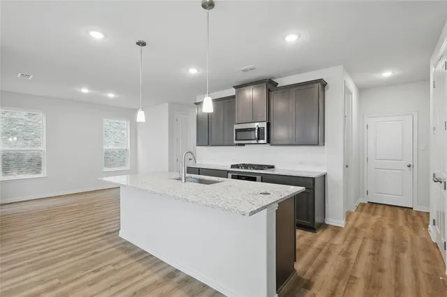 a kitchen with a sink stove and wooden floor