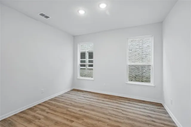 a view of a kitchen and an empty room with wooden floor and a window