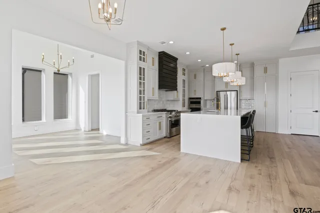 a view of kitchen with kitchen island stainless steel appliances refrigerator stove and wooden floor