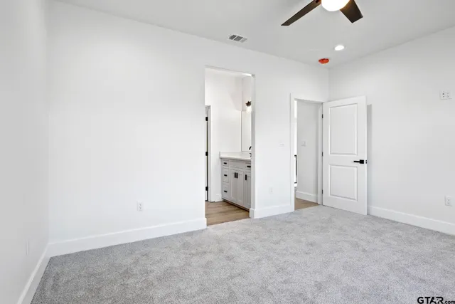 an empty room with chandelier fan and windows