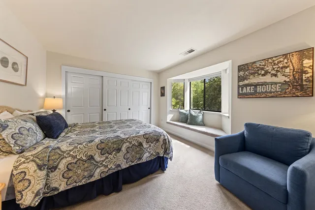 a bedroom with a large bed couch and two large window