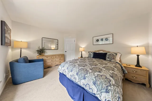 a spacious bedroom with a bed a couch and a lamp on table