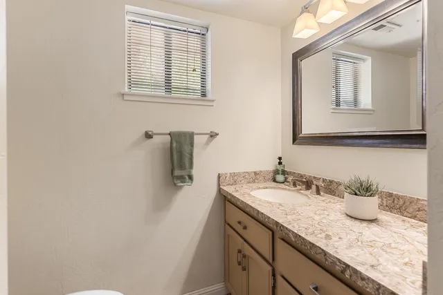 a bathroom with a granite countertop sink and a window