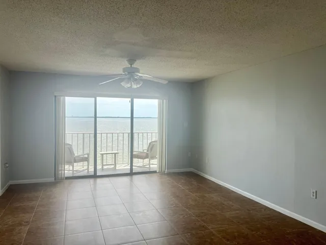 an empty room with windows and chandelier fan