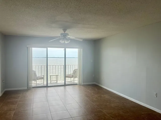 an empty room with windows and chandelier fan