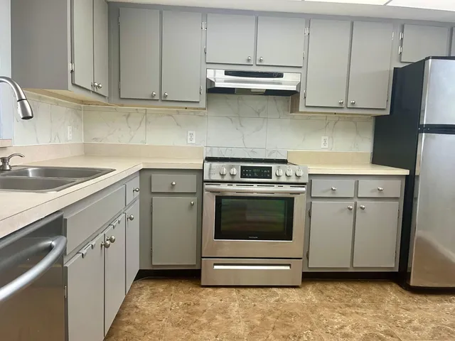 a kitchen with stainless steel appliances granite countertop a sink a stove and cabinets