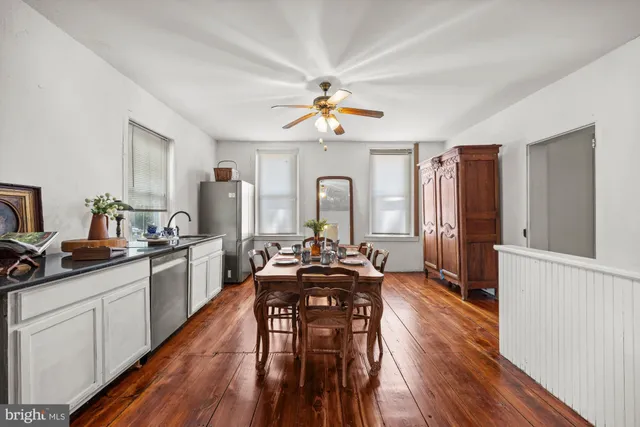 a large kitchen with sink a refrigerator and wooden floors